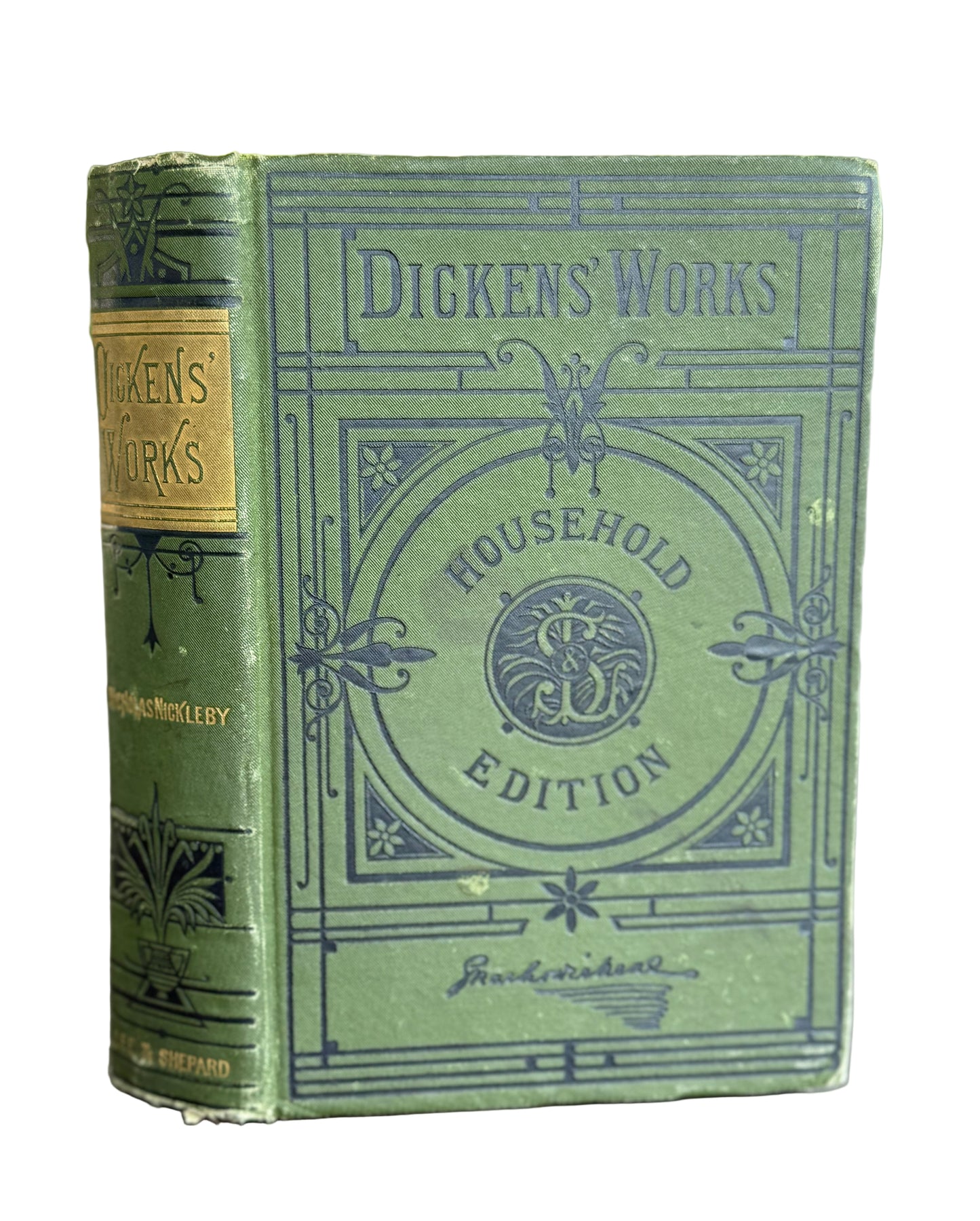Vintage green book titled 'Dickens' Works' with decorative cover on a wooden surface.