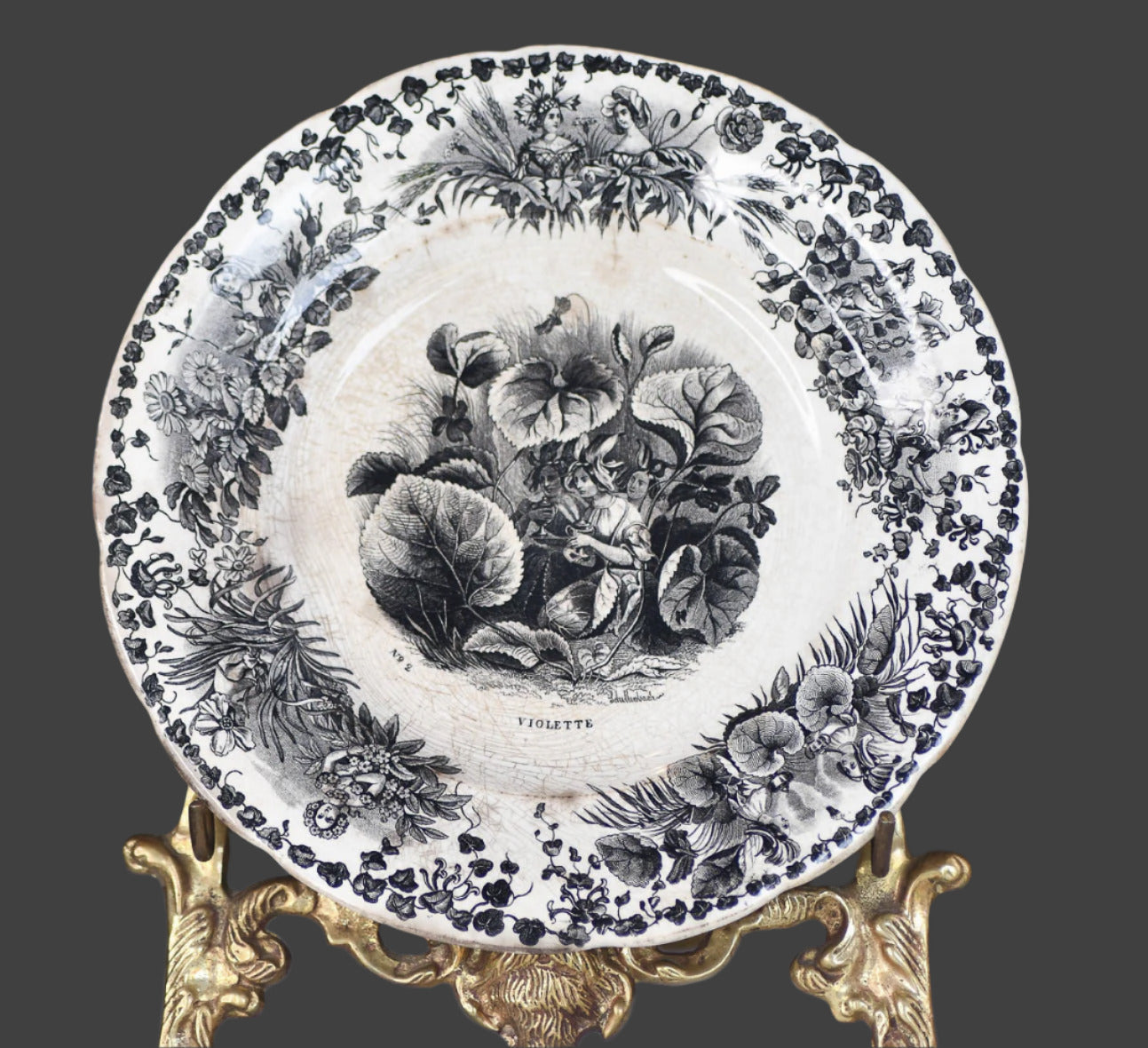 Decorative plate with black floral design on a decorative stand