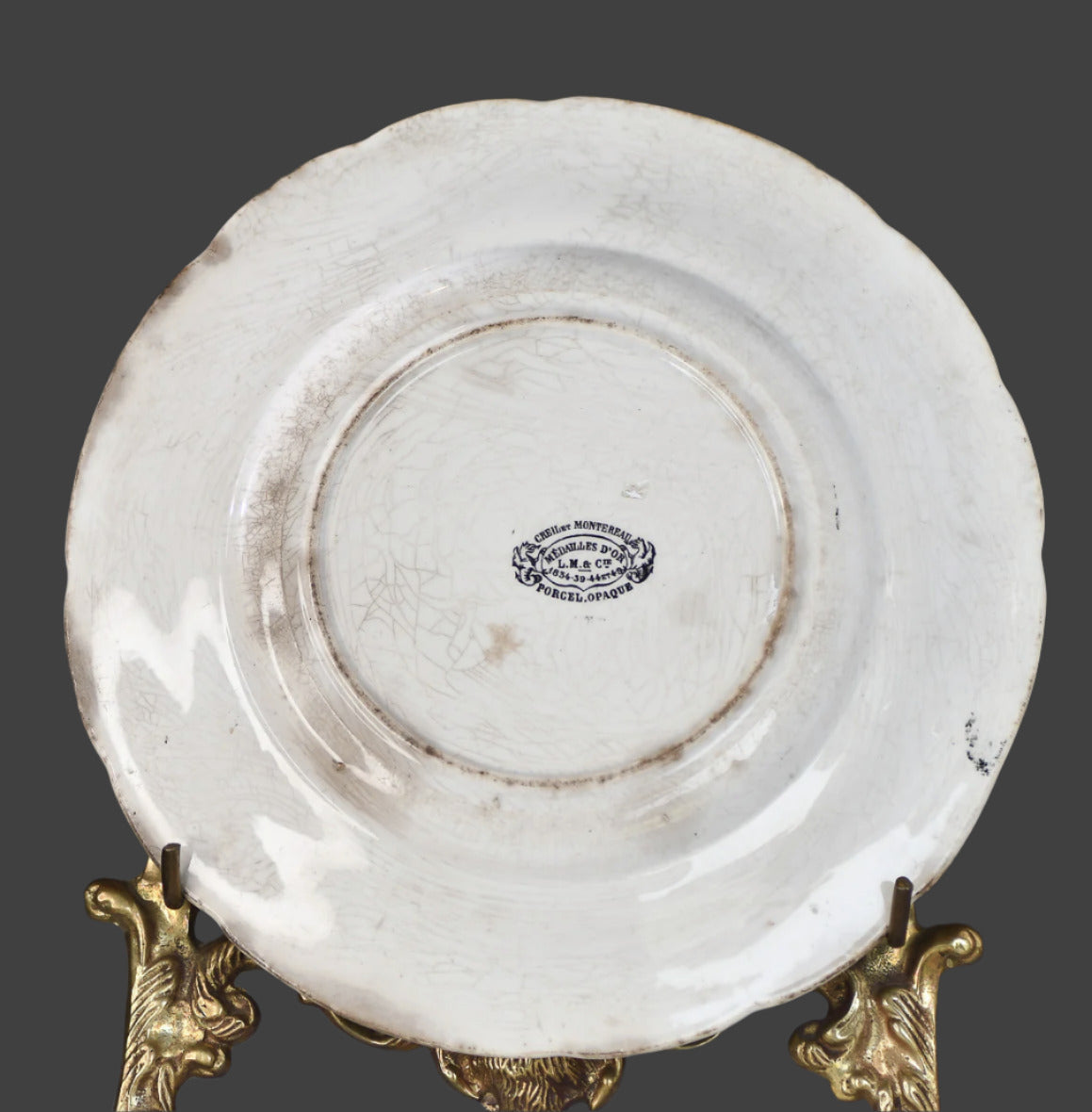 White ceramic plate with gold stand on a dark background