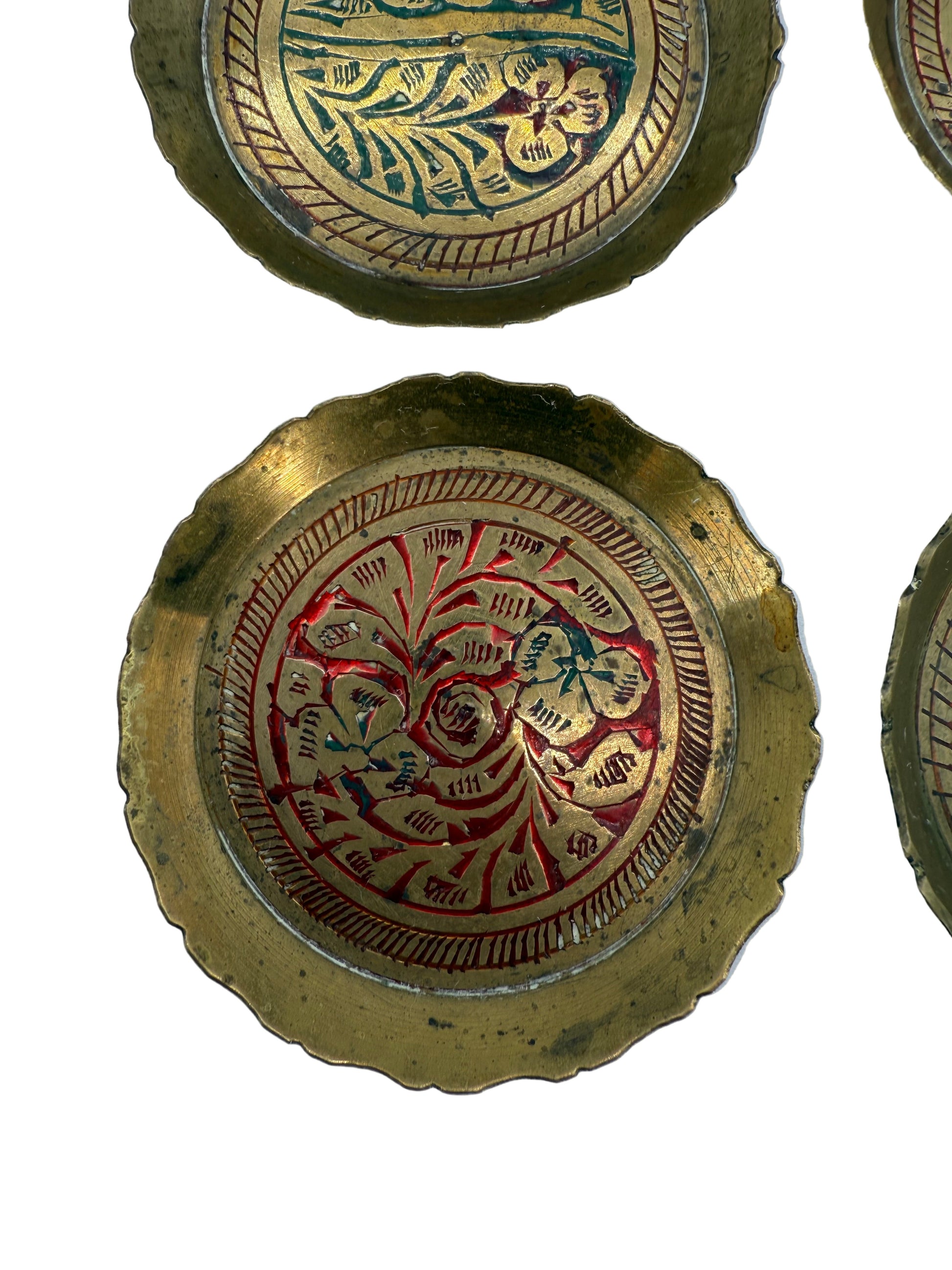 Decorative brass plates with intricate designs on a white background