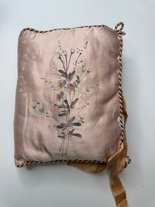 Decorative pillow with floral embroidery on a light gray background