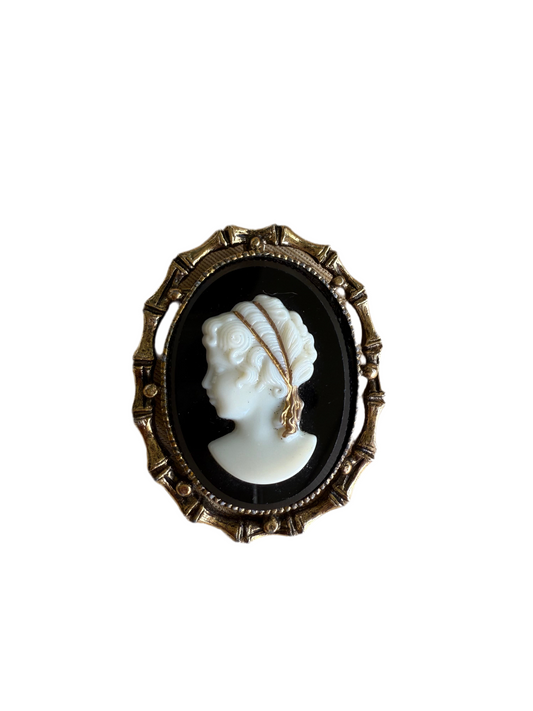 Cameo brooch with a profile of a woman's face in a gold frame on a white background