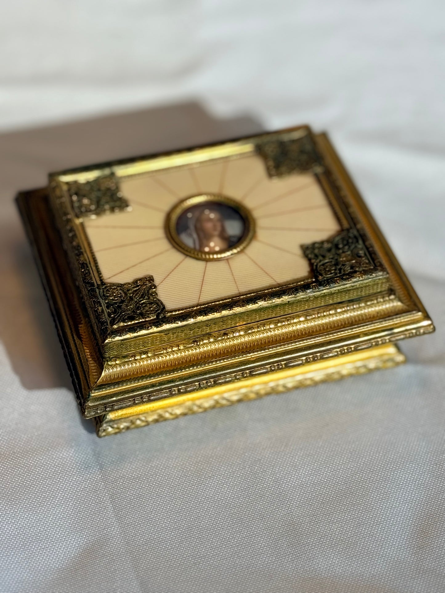 Decorative gold box with a portrait on a white fabric background
