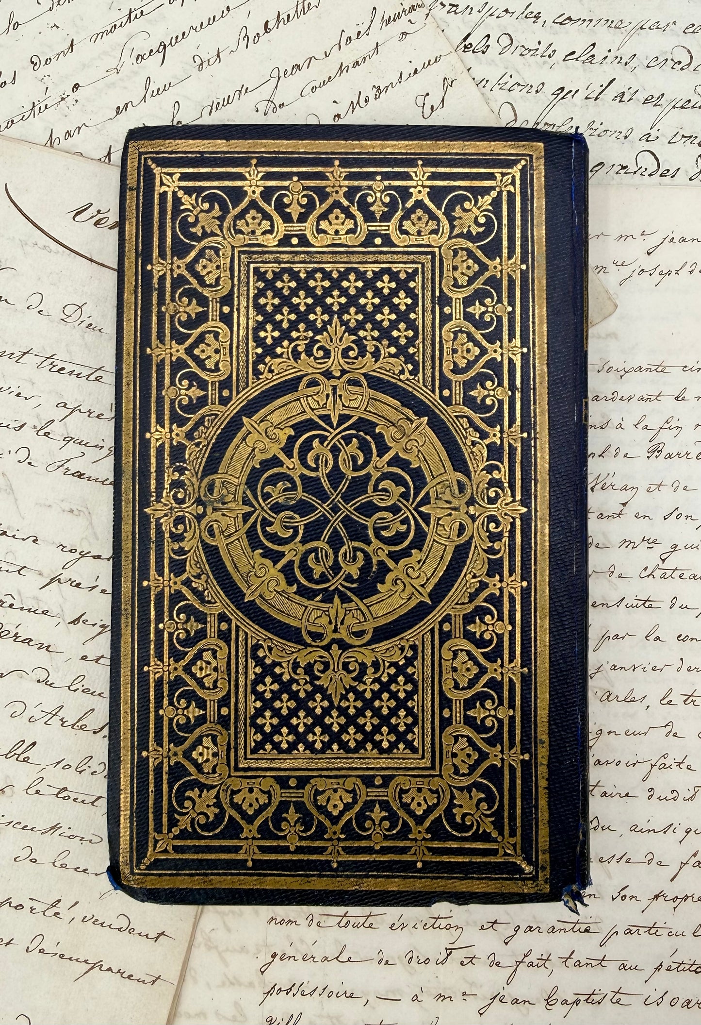 Decorative black book with gold patterns on a sheet of handwritten text