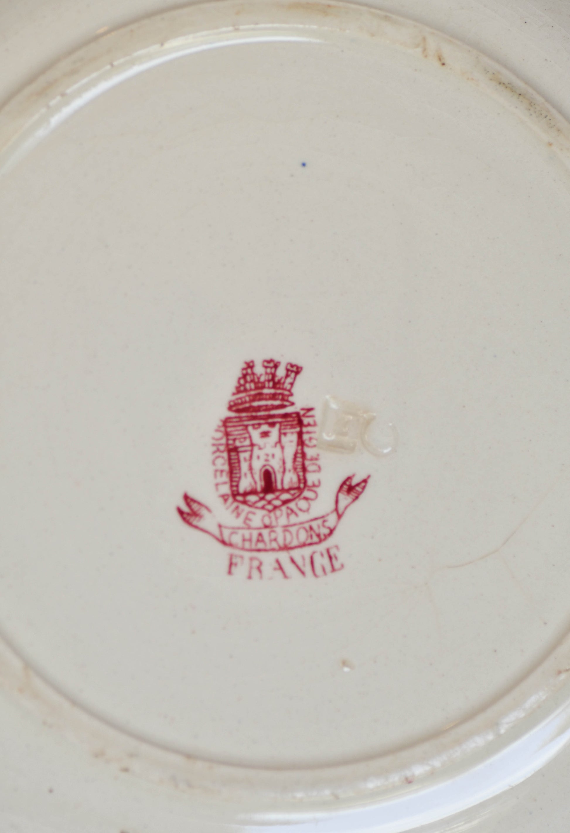 Close-up of a red logo and text on a white ceramic plate.