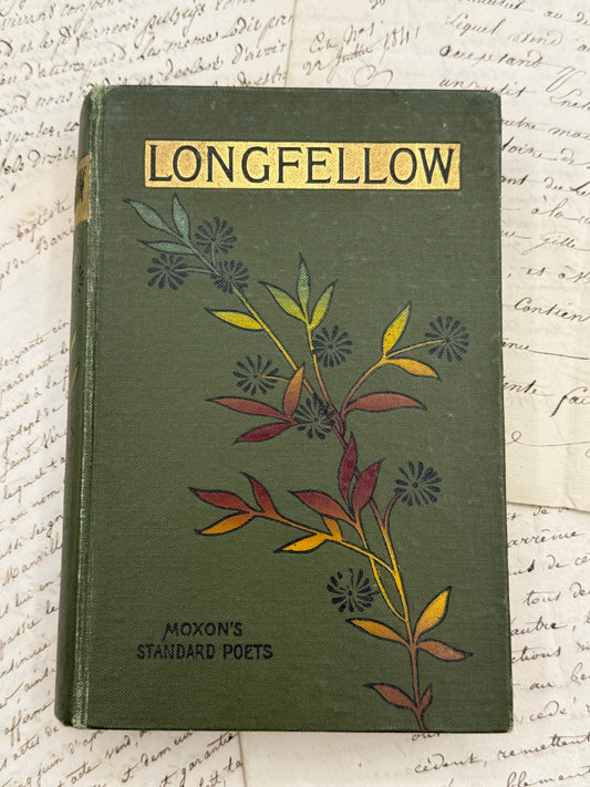 Vintage book titled 'Longfellow' with floral design on a textured background