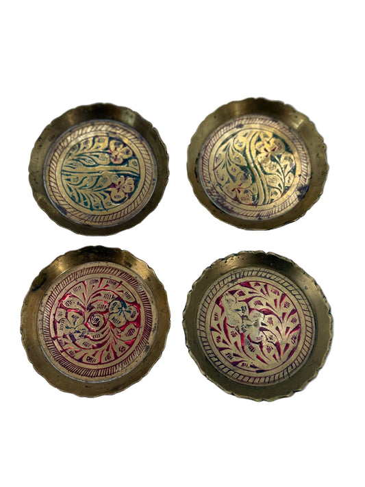 Four ornate brass buttons with intricate designs on a light blue background