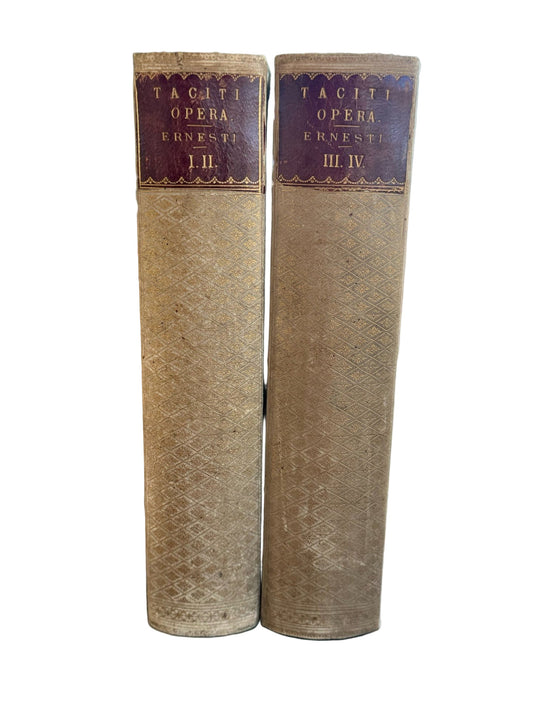 Two vintage books with decorative spines on a wooden surface.