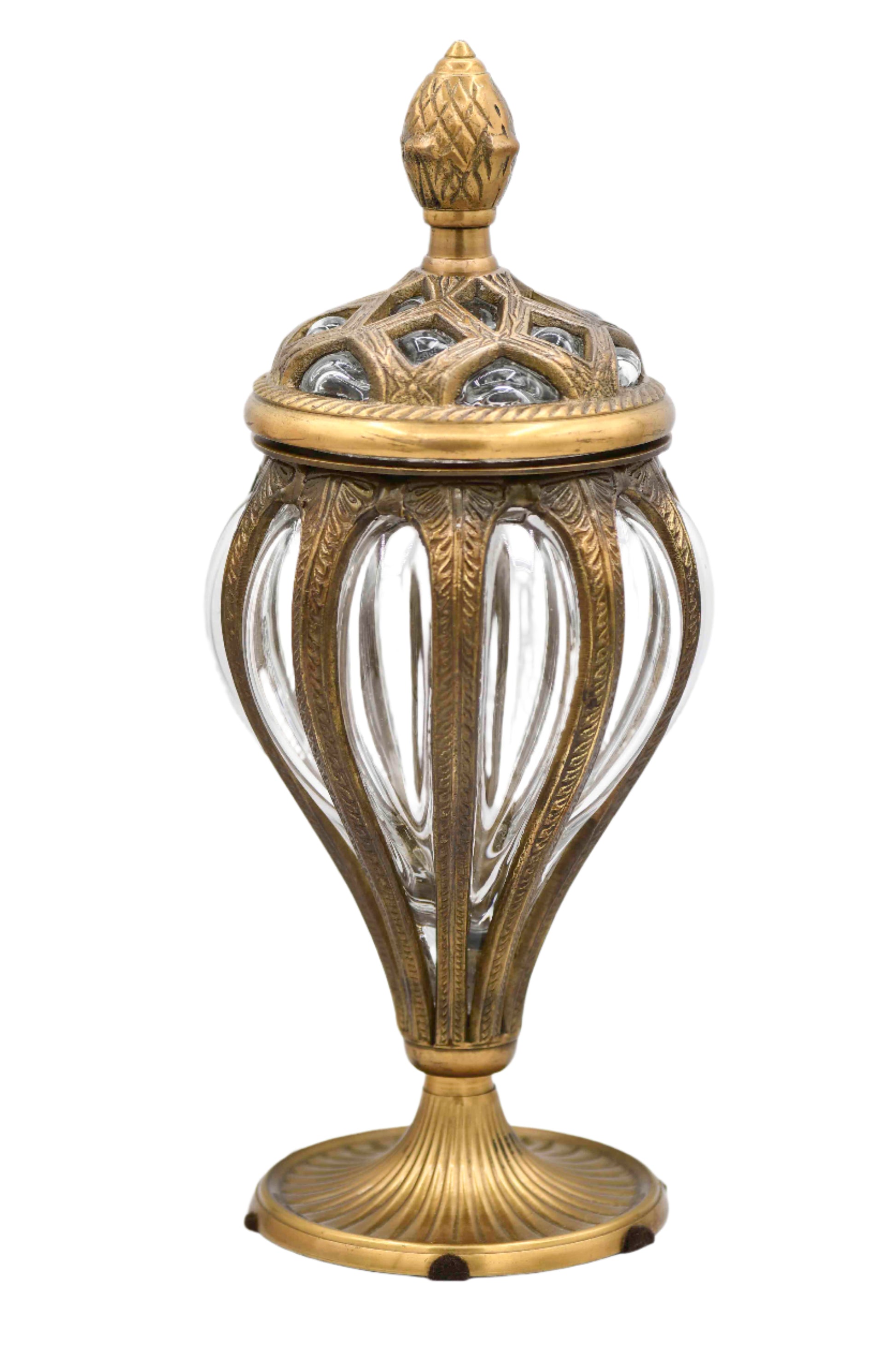 A vintage bubble glass apothecary jar with brass embellishments and a decorative lid, featuring an embossed design and a finial on top.