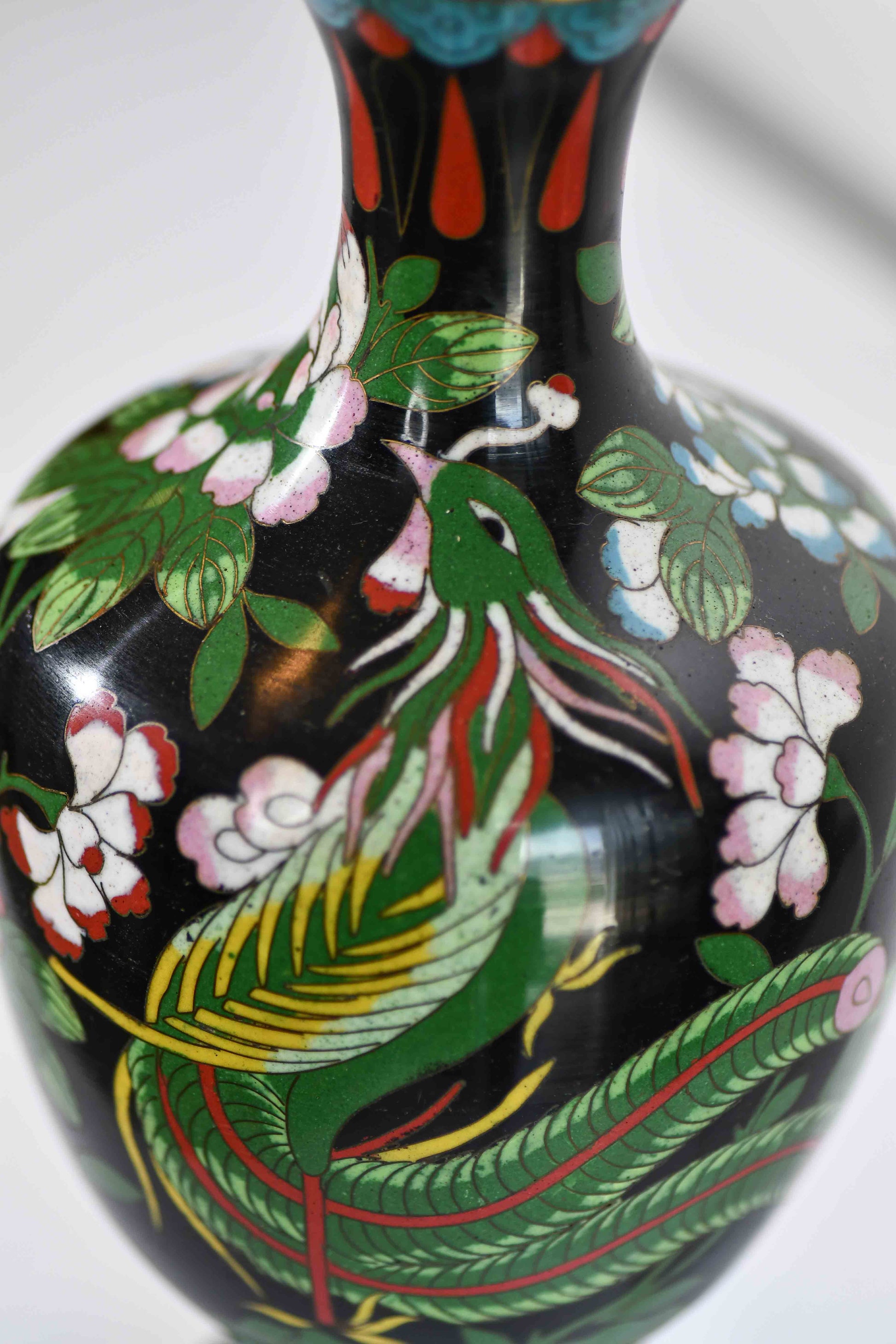 Decorative vase with peacock and floral design on a black background.